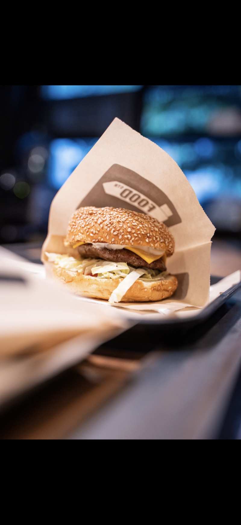 FOOD Str cheeseburger in branded kraft paper wrap with neon lights