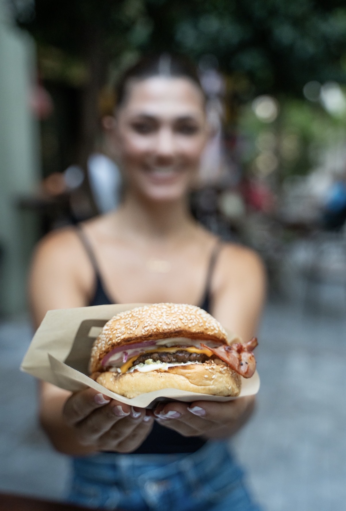 Woman holding a FOOD Str bacon cheeseburger in Monastiraki Athens